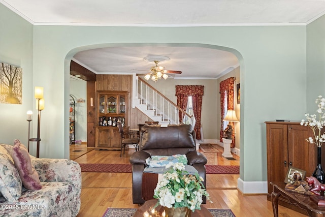 341 Dewart St, Danville, PA 17821 - living room featuring arched walkways, light wood-style flooring, stairs, ceiling fan, and crown molding