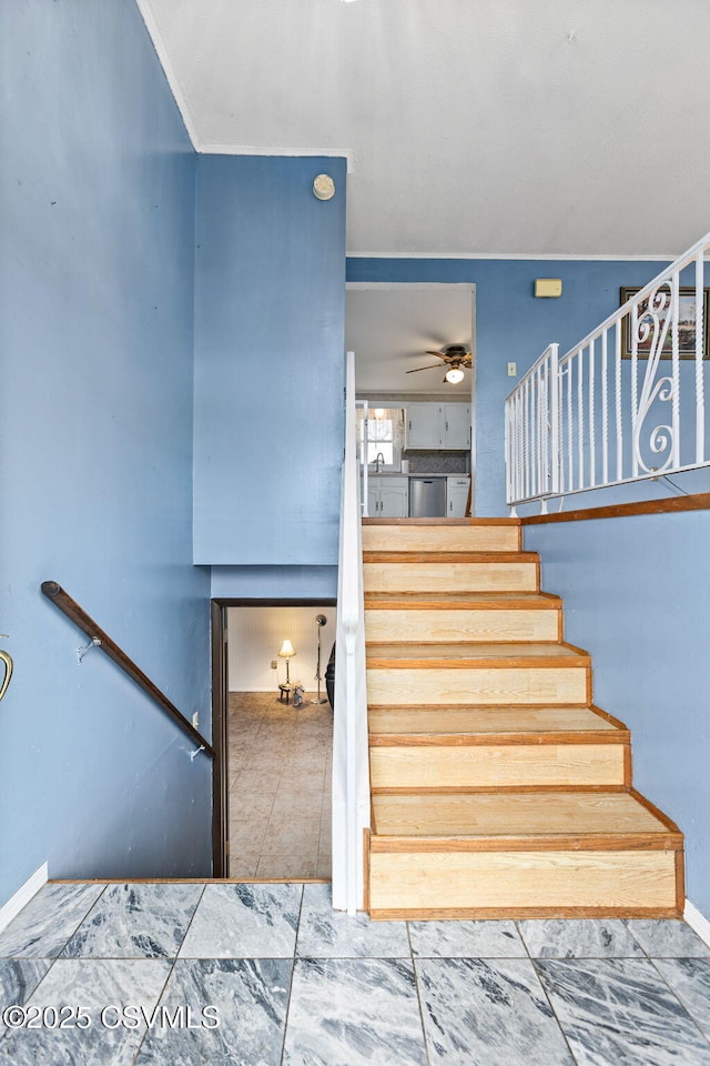 stairway with ceiling fan and baseboards