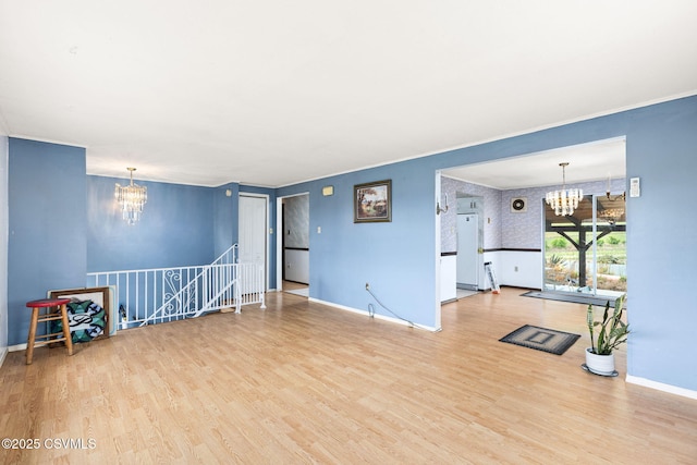 living room featuring a chandelier, baseboards, wood finished floors, and crown molding