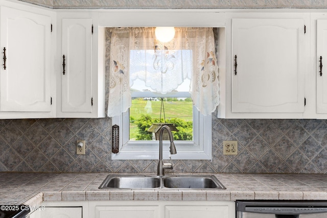 kitchen featuring a sink, stainless steel dishwasher, white cabinets, and decorative backsplash