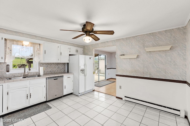 kitchen with stainless steel dishwasher, white fridge with ice dispenser, a sink, a baseboard heating unit, and white cabinetry