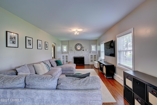 120 Geise St, Sunbury, PA 17801 - living area with baseboard heating, dark wood-style flooring, a brick fireplace, and arched walkways