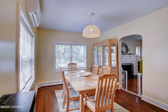 120 Geise St, Sunbury, PA 17801 - dining room with a wall mounted AC, baseboard heating, arched walkways, wood finished floors, and a brick fireplace