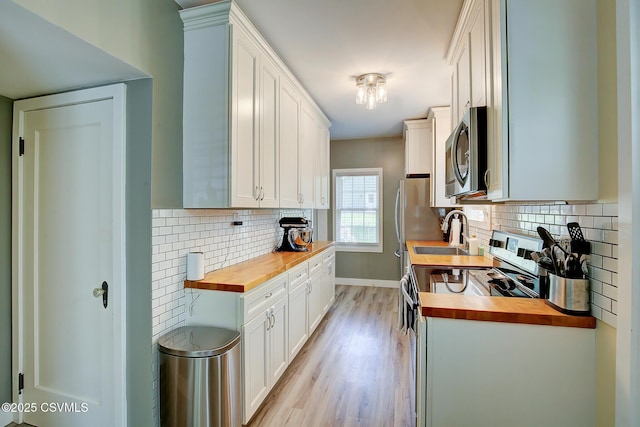120 Geise St, Sunbury, PA 17801 - kitchen featuring butcher block countertops, stainless steel appliances, a sink, white cabinetry, and light wood finished floors
