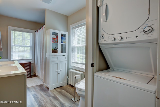 120 Geise St, Sunbury, PA 17801 - laundry area with radiator heating unit, stacked washer / dryer, light wood finished floors, and healthy amount of natural light