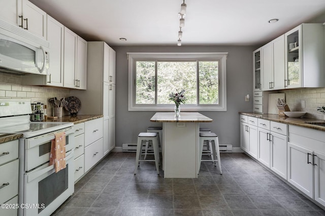 78 Trillium Ln, Danville, PA 17821 - kitchen featuring white appliances, a kitchen bar, tasteful backsplash, glass insert cabinets, and baseboards