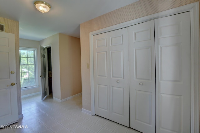 unfurnished bedroom with baseboards, a closet, and wallpapered walls