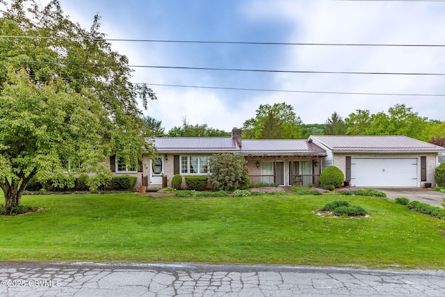 ranch-style home featuring a chimney, asphalt driveway, an attached garage, metal roof, and a front lawn