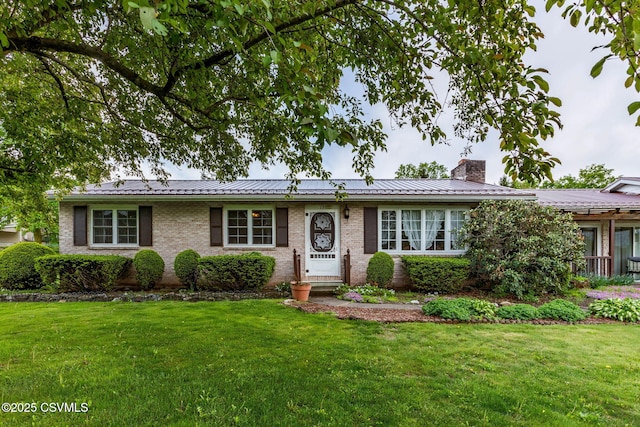 single story home with a chimney, a front yard, metal roof, and brick siding