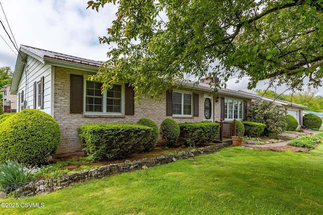 ranch-style home featuring a garage, a front yard, metal roof, and stone siding