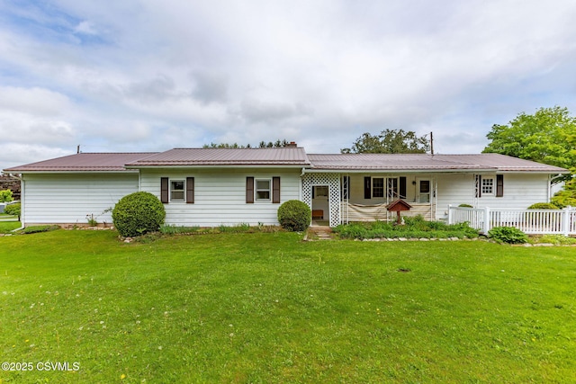 rear view of property with a lawn and metal roof