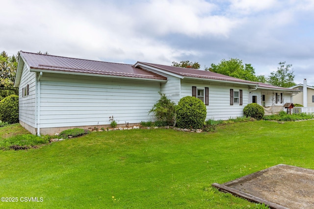 view of side of property with a lawn and metal roof