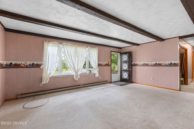 empty room with baseboard heating, beamed ceiling, baseboards, wooden walls, and carpet