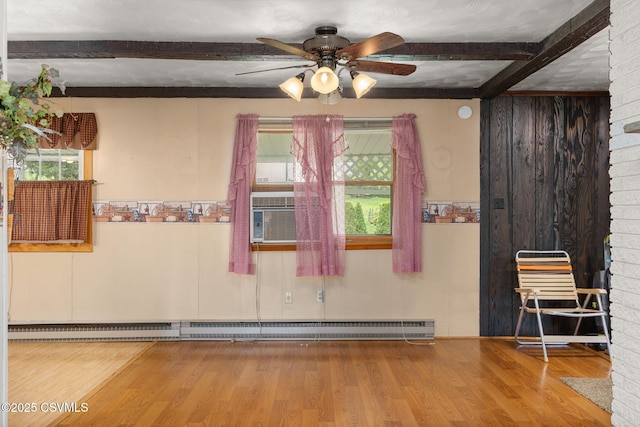 unfurnished room with beamed ceiling, a baseboard heating unit, plenty of natural light, a ceiling fan, and wood finished floors