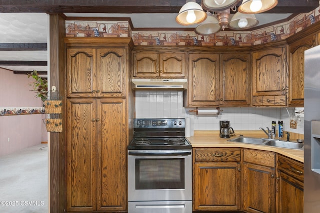 kitchen featuring appliances with stainless steel finishes, a sink, under cabinet range hood, decorative backsplash, and brown cabinetry