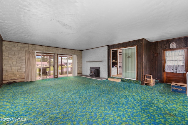unfurnished living room featuring wooden walls, carpet, and a textured ceiling