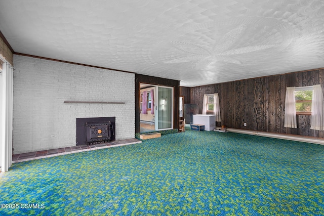 unfurnished living room with a textured ceiling, wooden walls, and carpet