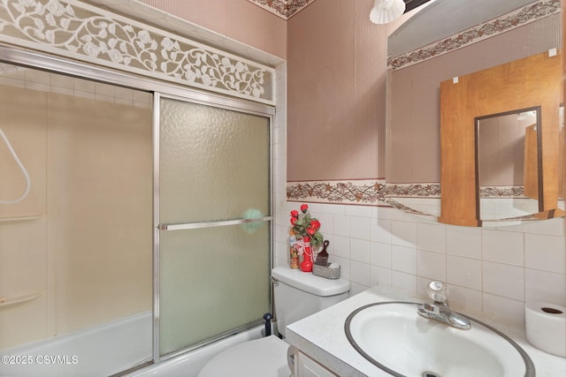 full bathroom with toilet, shower / bath combination with glass door, vanity, and tile walls