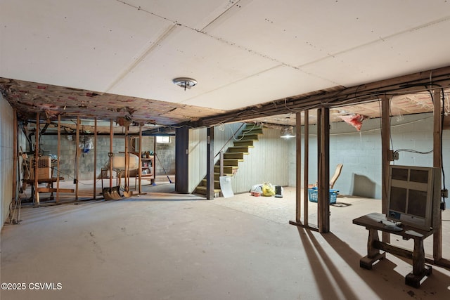 unfinished basement featuring stairs and heating unit