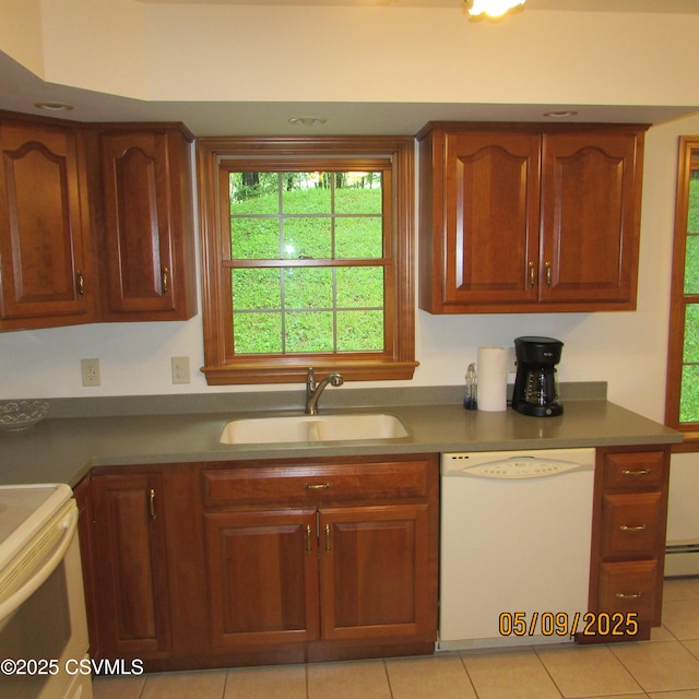 kitchen featuring white appliances, a sink, light tile patterned floors, and brown cabinetry