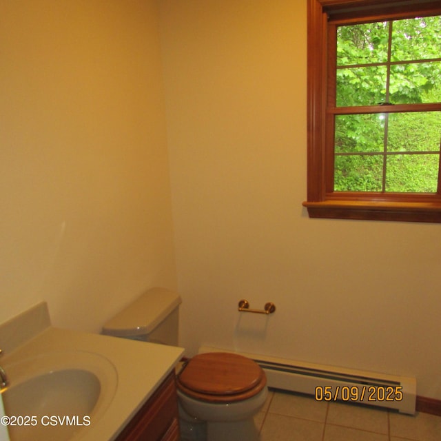 half bath with baseboard heating, plenty of natural light, vanity, and tile patterned flooring