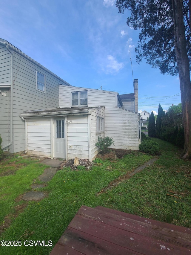 rear view of house featuring a yard and a chimney