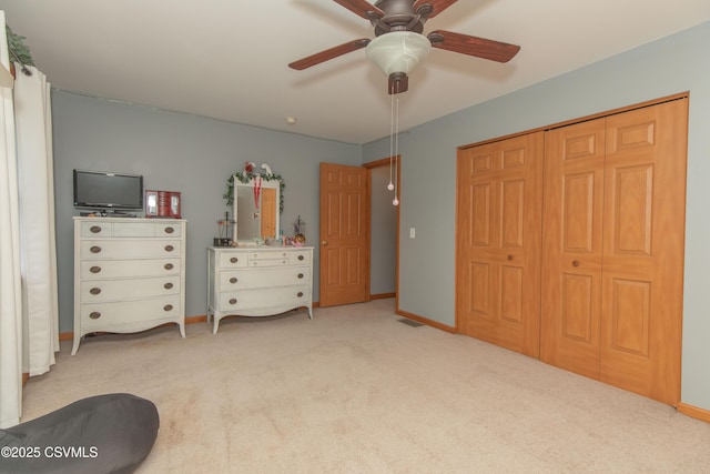 carpeted bedroom with ceiling fan, a closet, and baseboards