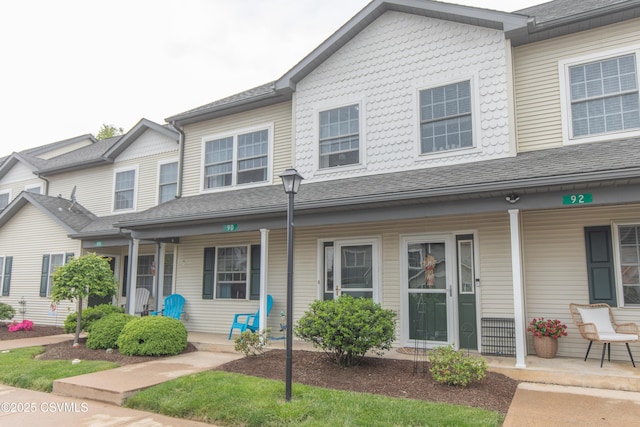 townhome / multi-family property with a porch and a shingled roof