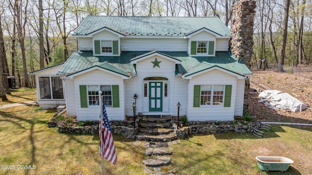 view of front of house featuring a sunroom, metal roof, and a front lawn