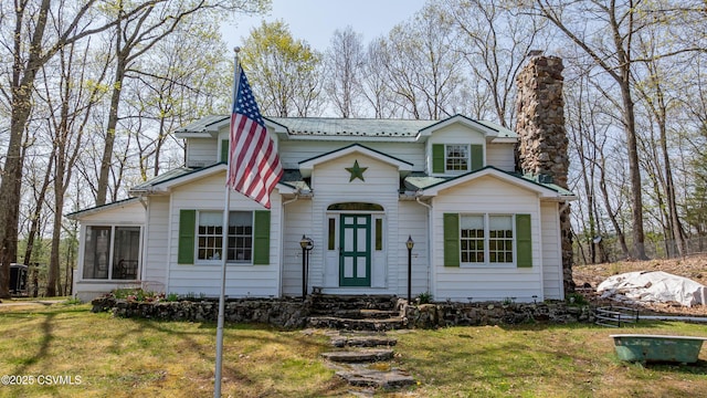 view of front of home with a chimney, a front yard, a sunroom, and metal roof
