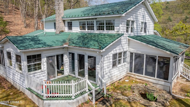 back of property with a sunroom and metal roof