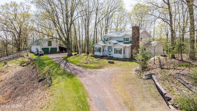 traditional-style house featuring driveway, an outdoor structure, a chimney, and a garage
