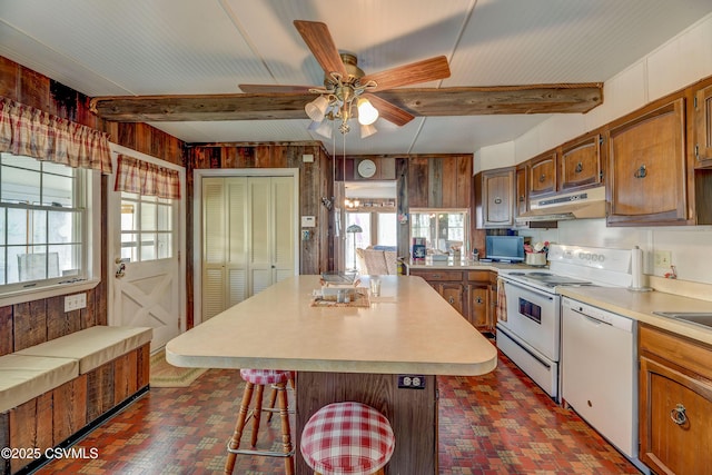 kitchen featuring wooden walls, white appliances, brick flooring, under cabinet range hood, and light countertops