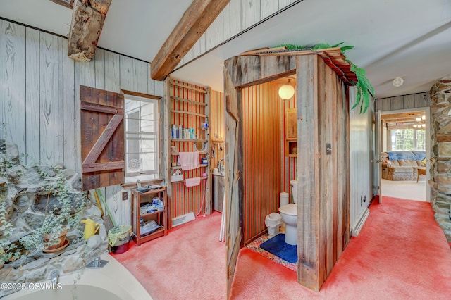 corridor featuring wood walls, carpet, and beamed ceiling