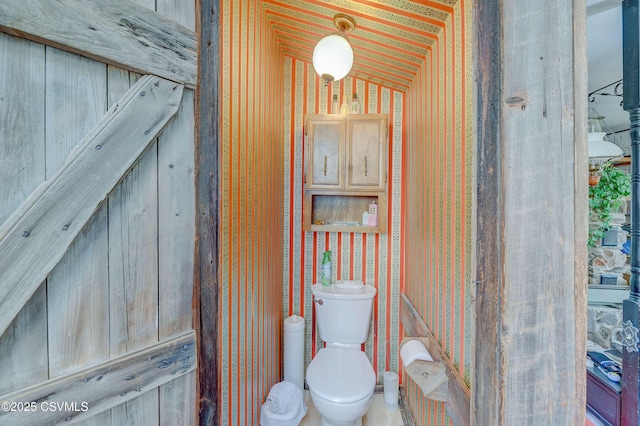 bathroom featuring toilet, lofted ceiling, and wallpapered walls