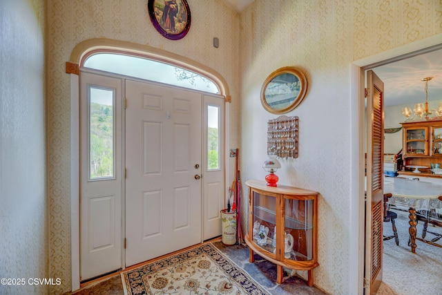 foyer entrance featuring a chandelier and wallpapered walls