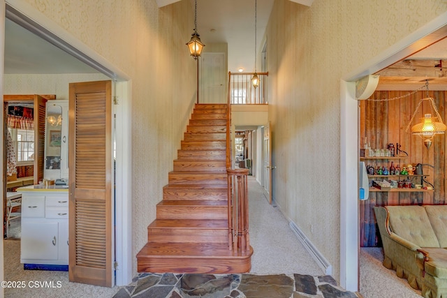 stairs featuring wallpapered walls, plenty of natural light, a high ceiling, and carpet floors