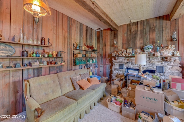 carpeted living area featuring wood walls, beamed ceiling, and a fireplace