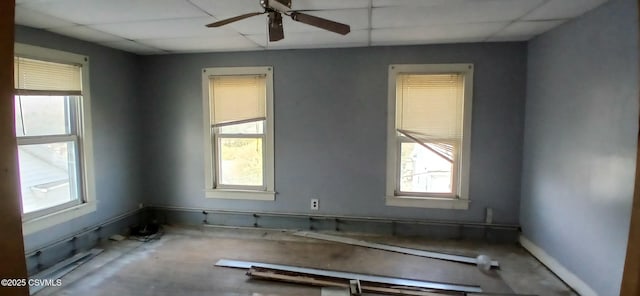 empty room featuring a paneled ceiling, plenty of natural light, and a ceiling fan