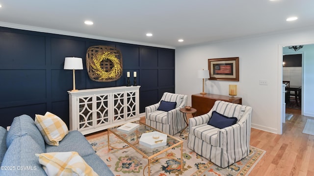 living room featuring light wood-type flooring, crown molding, recessed lighting, a decorative wall, and baseboards
