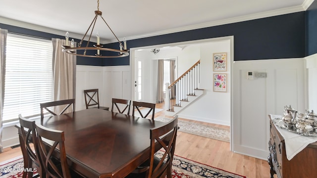 dining area featuring a chandelier, healthy amount of natural light, light wood finished floors, stairs, and crown molding