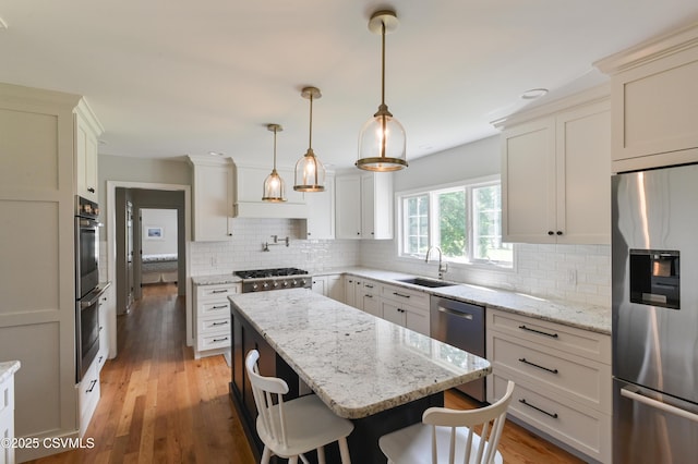 kitchen with stainless steel appliances, a sink, a center island, backsplash, and a kitchen breakfast bar