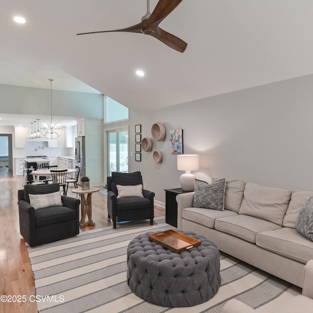 living area featuring a chandelier, ceiling fan, light wood-style flooring, recessed lighting, and high vaulted ceiling