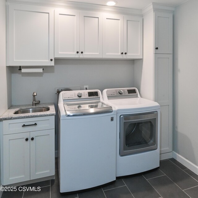 laundry room with washer and clothes dryer, cabinet space, dark tile patterned floors, and baseboards