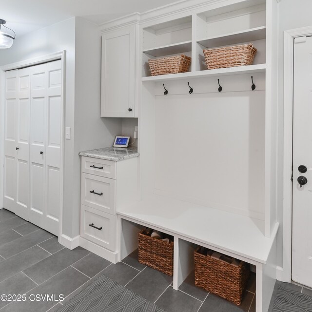 mudroom with baseboards and dark tile patterned floors