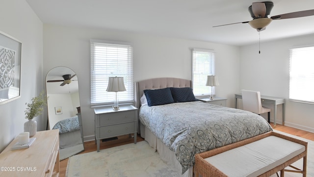 bedroom with light wood-style flooring, baseboards, and a ceiling fan