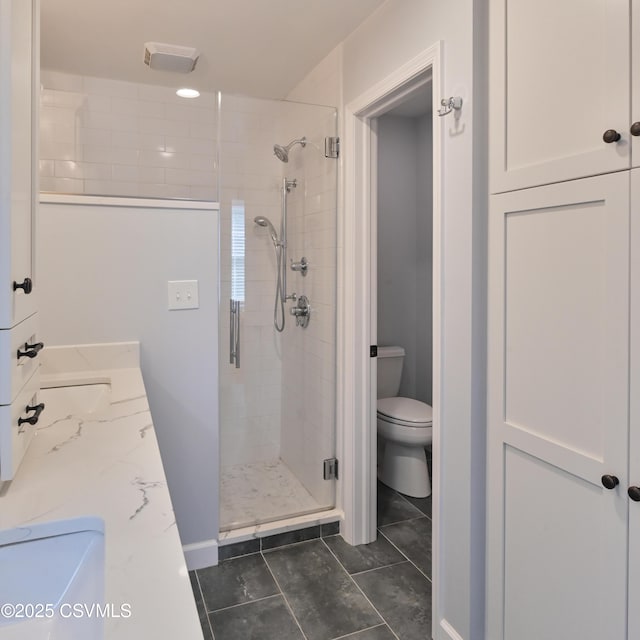 bathroom featuring toilet, a stall shower, and tile patterned flooring