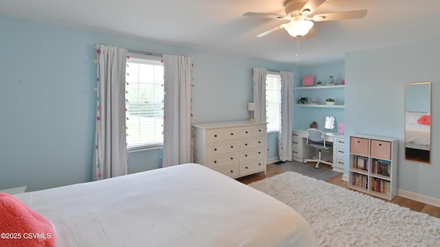 bedroom featuring wood finished floors, multiple windows, ceiling fan, and baseboards