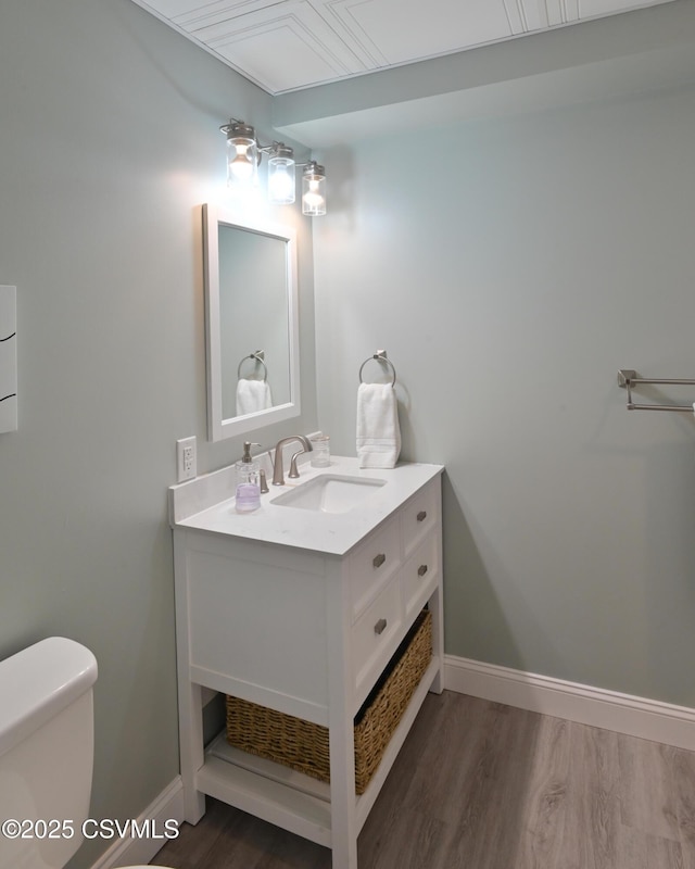 bathroom featuring wood finished floors, vanity, toilet, and baseboards