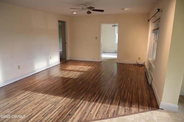 spare room with a baseboard heating unit, wood-type flooring, ceiling fan, and baseboards